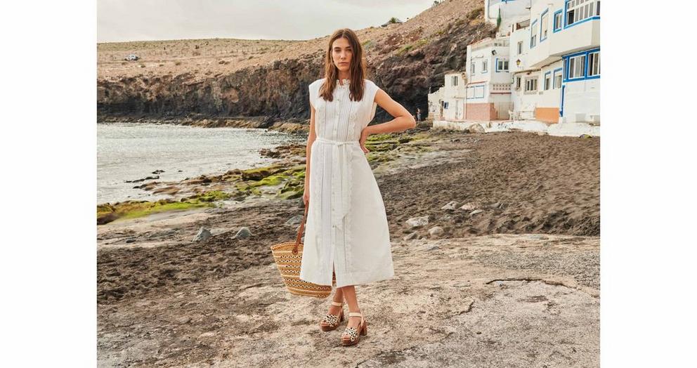 Woman at beach in white broderie dress